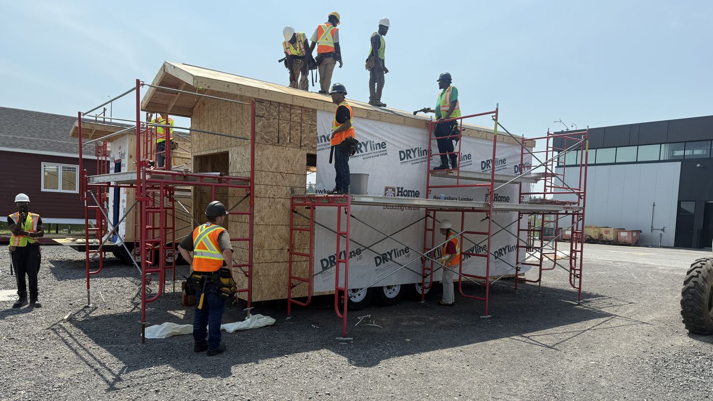 Collège La Cité students framing and sheathing a tiny home roof on scaffolding